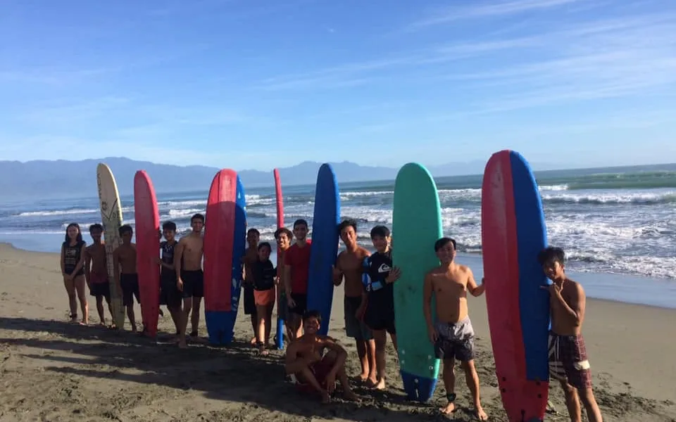 Young surfers standing with their El Dawn soft-top boards on Sabang Beach